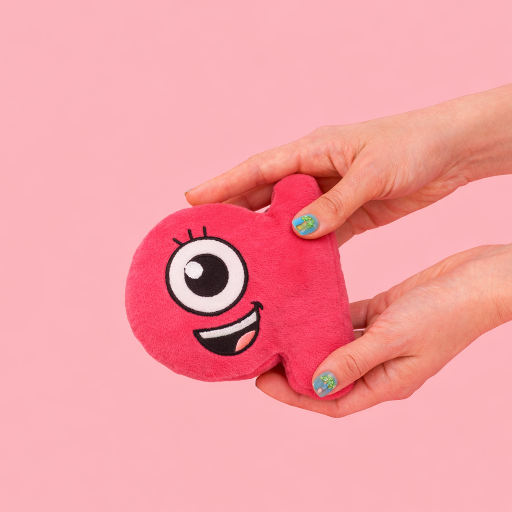 Pink plush toy with a face held by a hand against a pink background